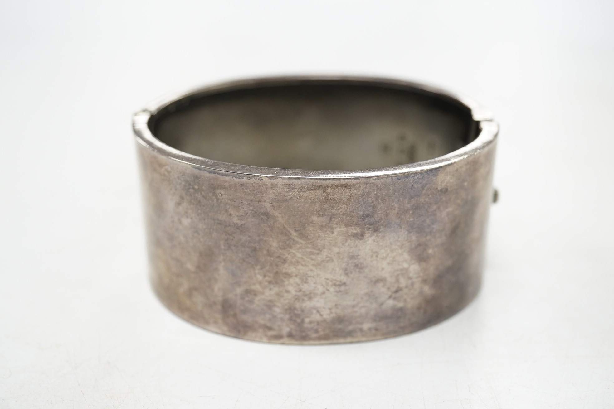 A George V engraved silver hinged bangle, with 'buckle' decoration, Kirwan & Co Ltd, Birmingham, 1913. Condition - poor to fair